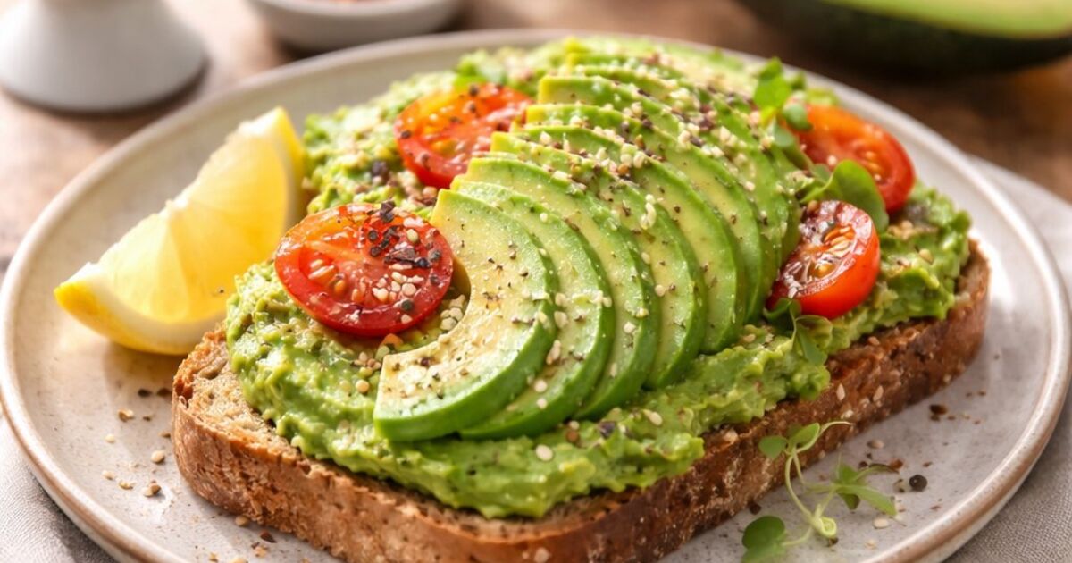 Tostada de aguacate con tomates cherry, semillas y limón sobre pan integral — desayuno saludable